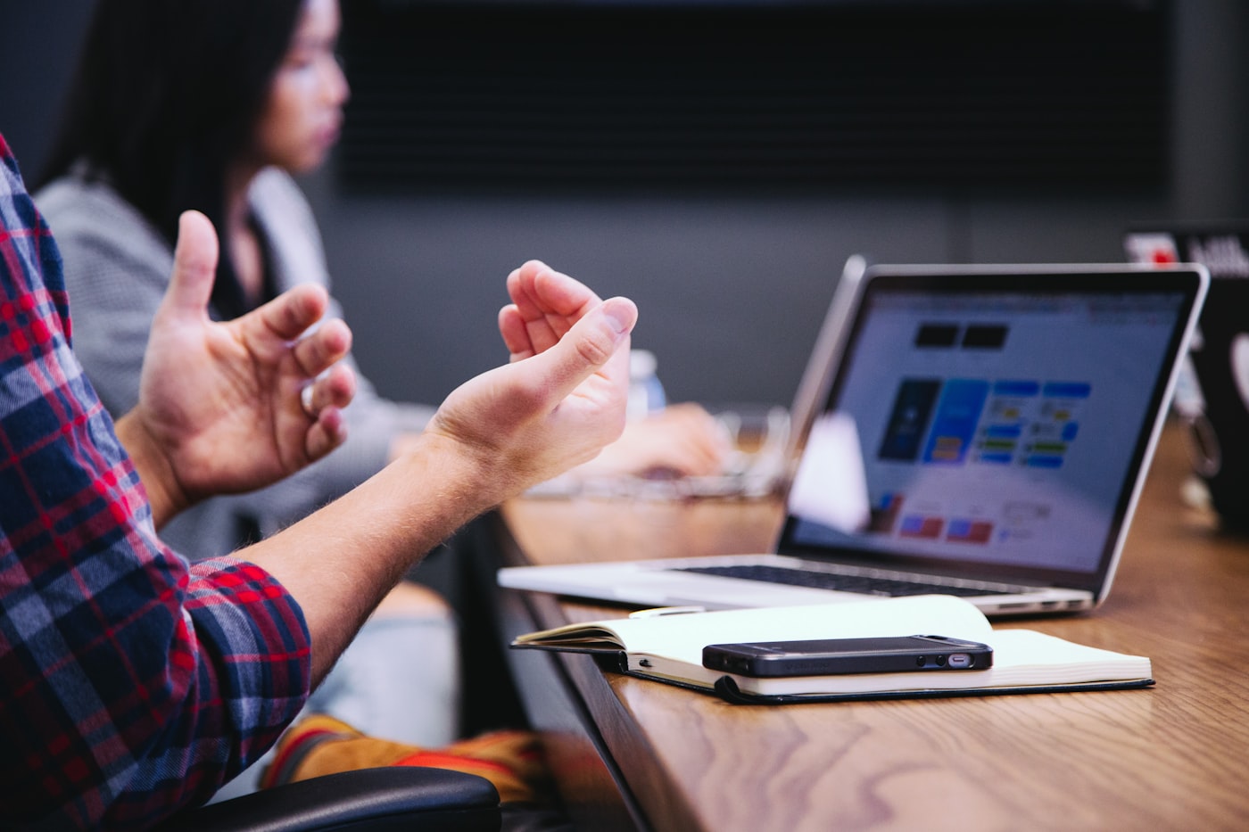 Two people in conversation over a laptop showing a project dashboard — the quiet working sessions where systems get designed, reviewed, and improved